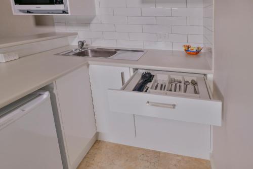 a white kitchen with a sink and a counter at Desert Palms Alice Springs in Alice Springs
