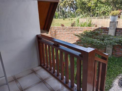 a wooden railing on a porch with a brick wall at Nan Bungalows Tetebatu in Tetebatu