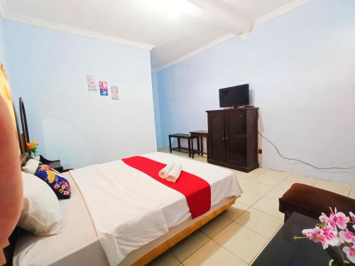a bedroom with a bed and a flat screen tv at YUTAKA INN Araya Malang in Blimbing