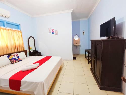a bedroom with a bed and a flat screen tv at YUTAKA INN Araya Malang in Blimbing