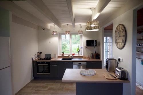 une cuisine avec des armoires noires et une horloge murale dans l'établissement Maison bretonne entre terre et mer, à Crozon