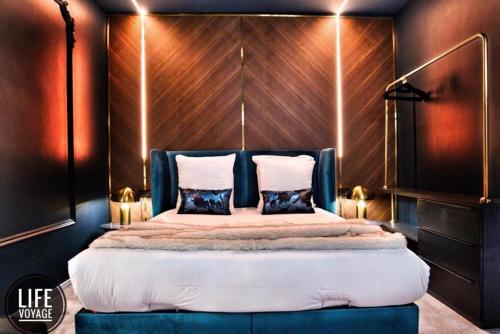 a bedroom with a large bed with a wooden wall at LiFE VOYAGE RESIDENCE & SPA - Strasbourg's City Center Luxury Experience in Strasbourg