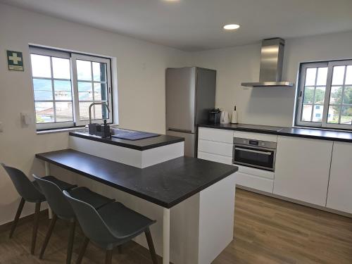 a kitchen with white cabinets and a black counter top at Destro village in Lindoso