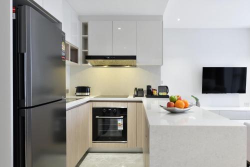 a kitchen with a stainless steel refrigerator and a bowl of fruit at GM Estate Hotel and Executive Apartments Sukhumvit 20 in Bangkok