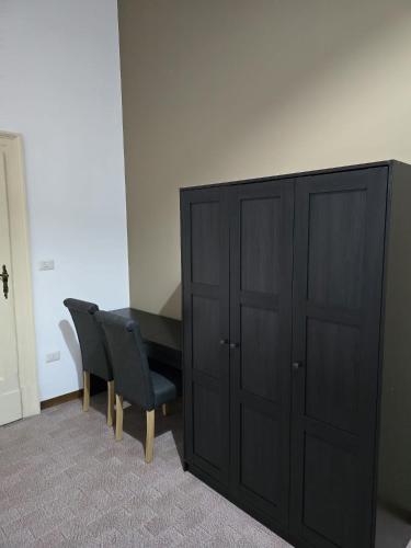 a bedroom with a bed and a black cabinet and a chair at Villa Terzaghi in Gorla Minore