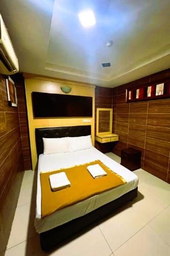a bedroom with a large bed with a yellow blanket at Ark Batu Caves Bussines Hotel in Batu Caves