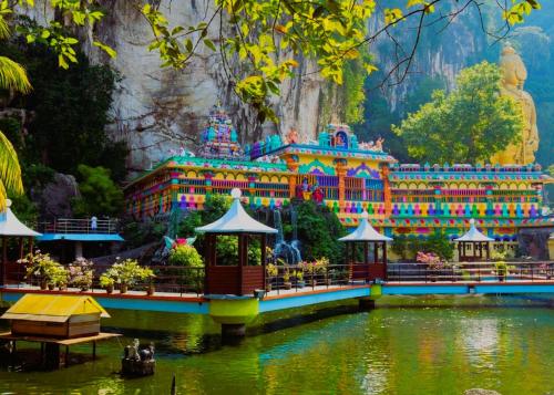 a temple in the middle of a lake in front of a mountain at Ark Batu Caves Bussines Hotel in Batu Caves