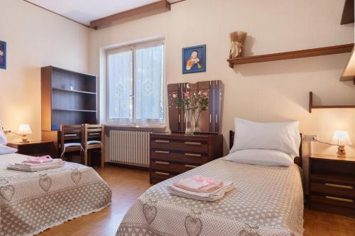 a bedroom with two beds and a desk and a window at Casa Rosanna al lago in Maccagno Inferiore