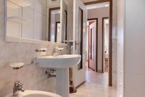 a white bathroom with a sink and a mirror at Casa Rosanna al lago in Maccagno Inferiore