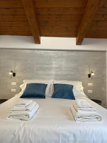 a bed with white sheets and blue pillows at Colle Rooms HELIANTHUS in Santa Maria degli Angeli