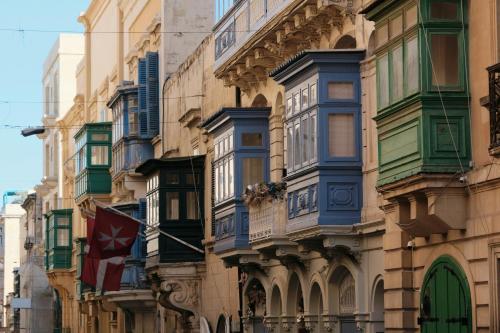 a building with colorful windows and a flag on a street at Stunning Holiday Home with Gorgeous Harbour Views in Senglea