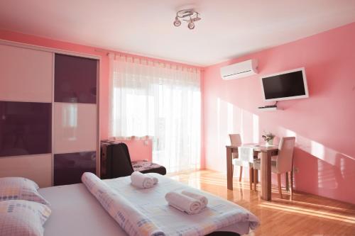Schlafzimmer mit rosa Wänden, einem Tisch und einem Bett in der Unterkunft Apartments Kristal in Kaštela