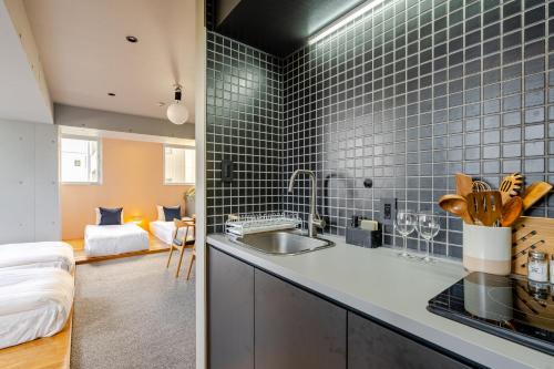 a kitchen with a sink and blue tiles on the wall at STAY ARI Shinjuku Takadanobaba Design awarded in Tokyo