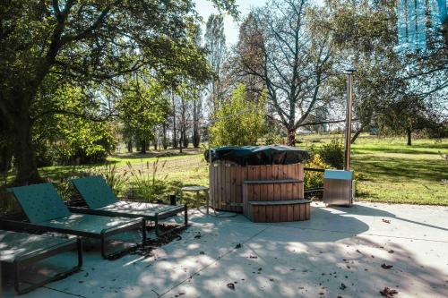 a park with a bench and a wooden barrel at Le verger de Paulin in Yvoir