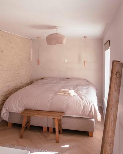 a bedroom with a bed and a wooden bench at Le verger de Paulin in Yvoir