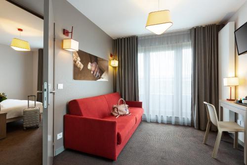 a hotel room with a red couch and a bed at Nehô Suites Porte de Genève - Gare Annemasse in Annemasse