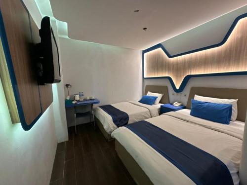 a hotel room with two beds and a flat screen tv at Golden Palace Hotel in Batu Merah