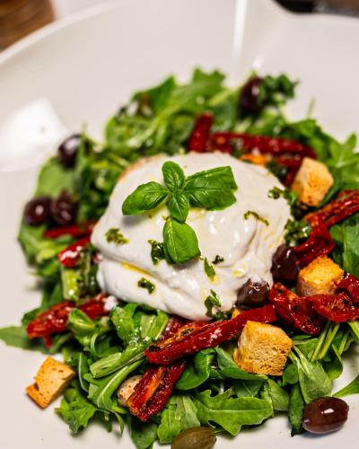a white plate with a salad with dressing on it at B&B Mio Nonno Rooms Ljubljana Ex Bizeljčan Rooms in Ljubljana