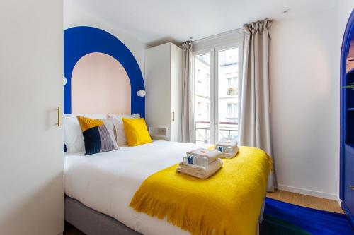 - une chambre avec un grand lit aux accents jaunes et bleus dans l'établissement Stunning apartment - 2BR-6P - Paris Center, à Paris