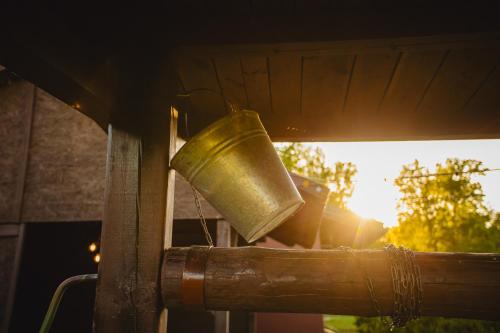 a brass bell hanging from a window with the sunset at Atpūtas namiņš Skudriņas in Sesava
