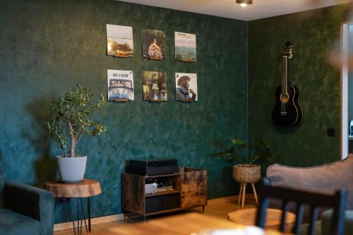 a living room with a green wall with a guitar at Atpūtas namiņš Skudriņas in Sesava