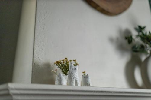 a shelf with two white figurines and a plant at Atpūtas namiņš Skudriņas in Sesava