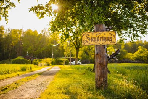 a sign on a tree on a dirt road at Atpūtas namiņš Skudriņas in Sesava