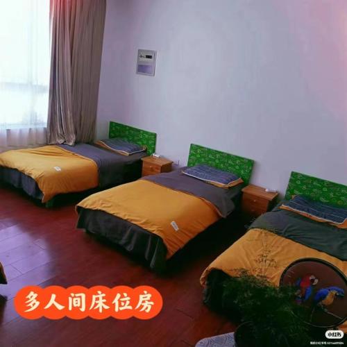 a room with three beds in it with an asian writing at 暖阳民宿 in Shigatse