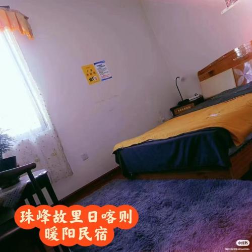 a bedroom with a bed with a purple rug and a window at 暖阳民宿 in Shigatse