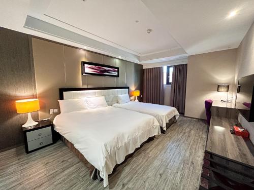 a hotel room with a large bed and two lamps at Royal Fine Hotel in Kaohsiung
