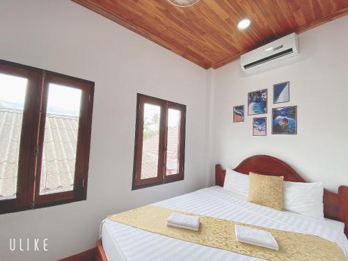 a bedroom with a bed and two windows at Elephant Boutique Hotel in Luang Prabang
