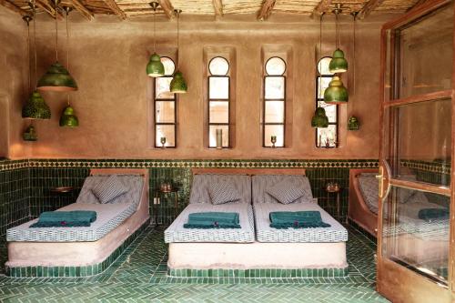 two beds in a room with two windows at Le Jardin des Douars in Ghazoua
