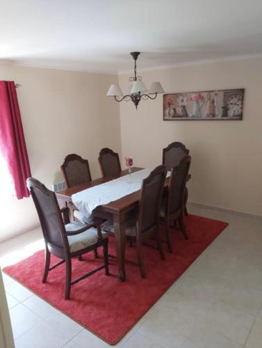 une salle à manger avec une table et des chaises sur un tapis rouge dans l'établissement Le Petit Parc, à Saint-Brice-de-Landelles