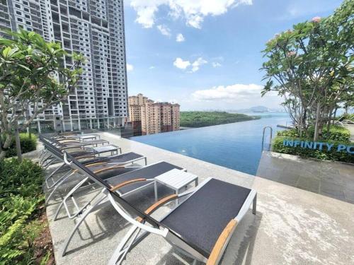 a row of chaise lounge chairs on a balcony overlooking a river at Urban Emerald Seaview 6Pax 3Queen 3Room 2Bath 2Carpark with Infinity Pool in Jelutong