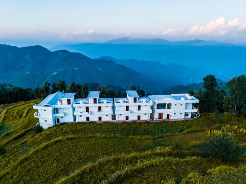 a group of white buildings on top of a hill at Maatidera Resort Kanatal The Boutique stay in the Lap of Himalayas in Kanatal