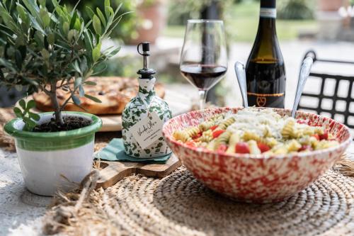 a table with a bowl of pasta and a glass of wine at VerdeOlivo 1876 - Apartments & Pool in Mezzane di Sotto