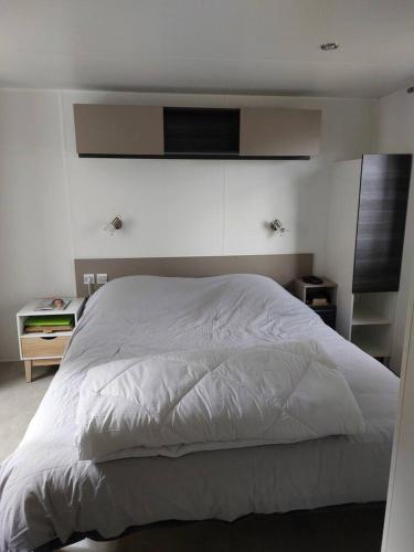 Cette chambre comprend un lit blanc et une télévision murale. dans l'établissement Mobilhome N 603 - camping 4étoiles - Tout confort au calme, à Gastes