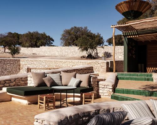 a patio with a couch and a table and chairs at Le Jardin des Douars in Ghazoua