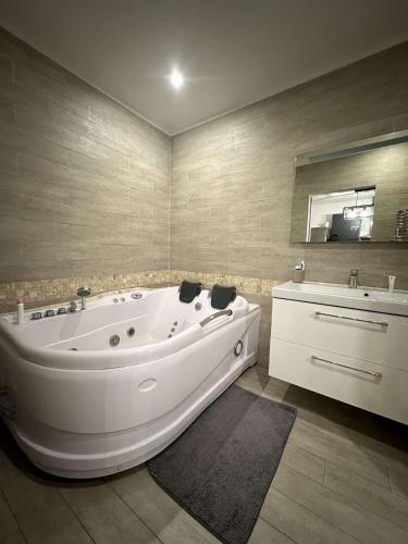 La salle de bains est pourvue d'une grande baignoire blanche et d'un lavabo. dans l'établissement Jacuzzi ciotat, à La Ciotat