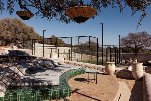 a patio with a couch and a table and a fence at Le Jardin des Douars in Ghazoua
