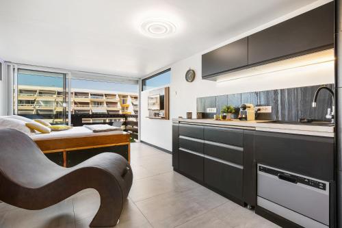 une cuisine avec des armoires noires et blanches et un évier dans l'établissement Village Naturiste R4N - Atypique Port Nature 1, au Cap d'Agde