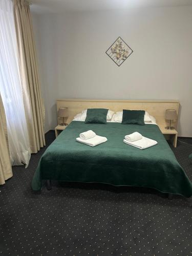 a bedroom with a green bed with two towels on it at Hotel Pacific in Timişoara
