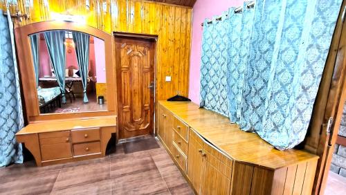 Un vestidor con espejo y una cómoda de madera. en Melody Orchard Cottage, en Jagatsukh