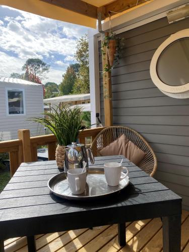 - une table avec un plateau de tasses à café sur la terrasse dans l'établissement Camping SIBLU Les Viviers 4 étoiles, à Lège-Cap-Ferret