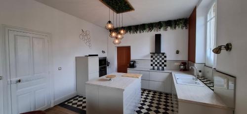 a kitchen with white cabinets and a black and white checkered floor at Le Grand Cru in Cramant