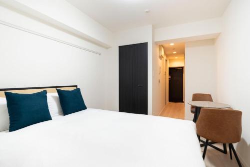 a bedroom with a white bed and a table and chairs at Leclerc Nishi-Shinjuku in Tokyo