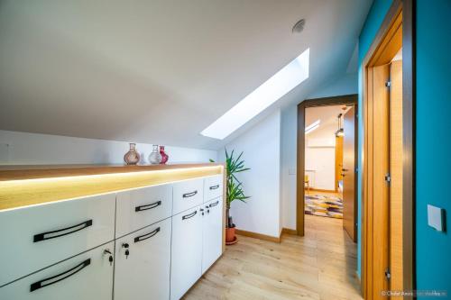 a kitchen with white cabinets and a blue wall at Anais Chalet in Câmpulung Moldovenesc