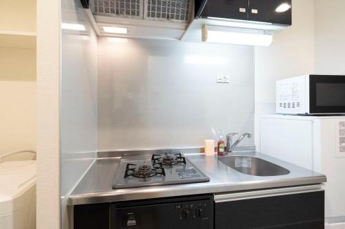 a kitchen with a stove and a sink and a microwave at Leclerc Nishi-Shinjuku in Tokyo