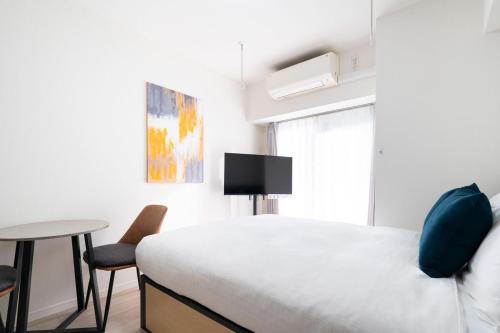 a bedroom with a bed and a table and a tv at Leclerc Nishi-Shinjuku in Tokyo