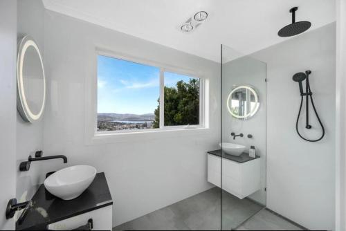 baño blanco con lavabo y ventana en Hobart Retreat with City and Water View, en West Hobart